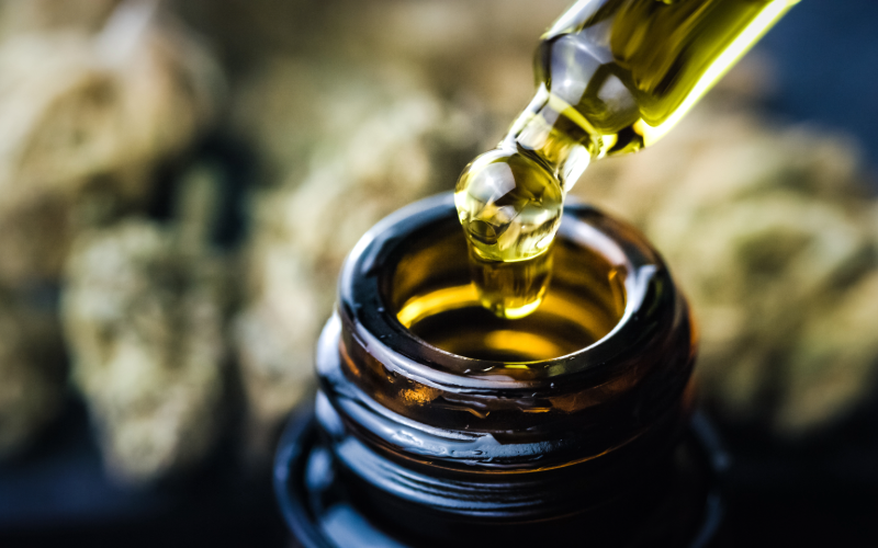 A close up photograph of a tincture dropper containing a clear, yellow oil.